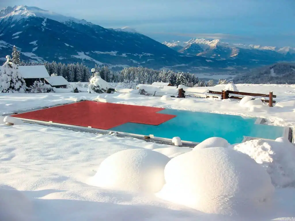 Hochwertiger Schwimmbadabdeckungen im winterlichen Bergpanorama, hergestellt aus langlebigen Materialien mit deutscher Ingenieurskunst.