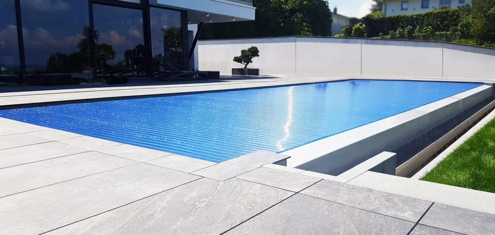 Hochwertiger Solar-Poolabdeckungsrollos mit modernem Design vor einem modernen Haus, aus langlebigen Materialien, deutsche Ingenieurskunst, sorgt für Energieeffizienz, Wärmegewinn und eleganten Poolschutz.