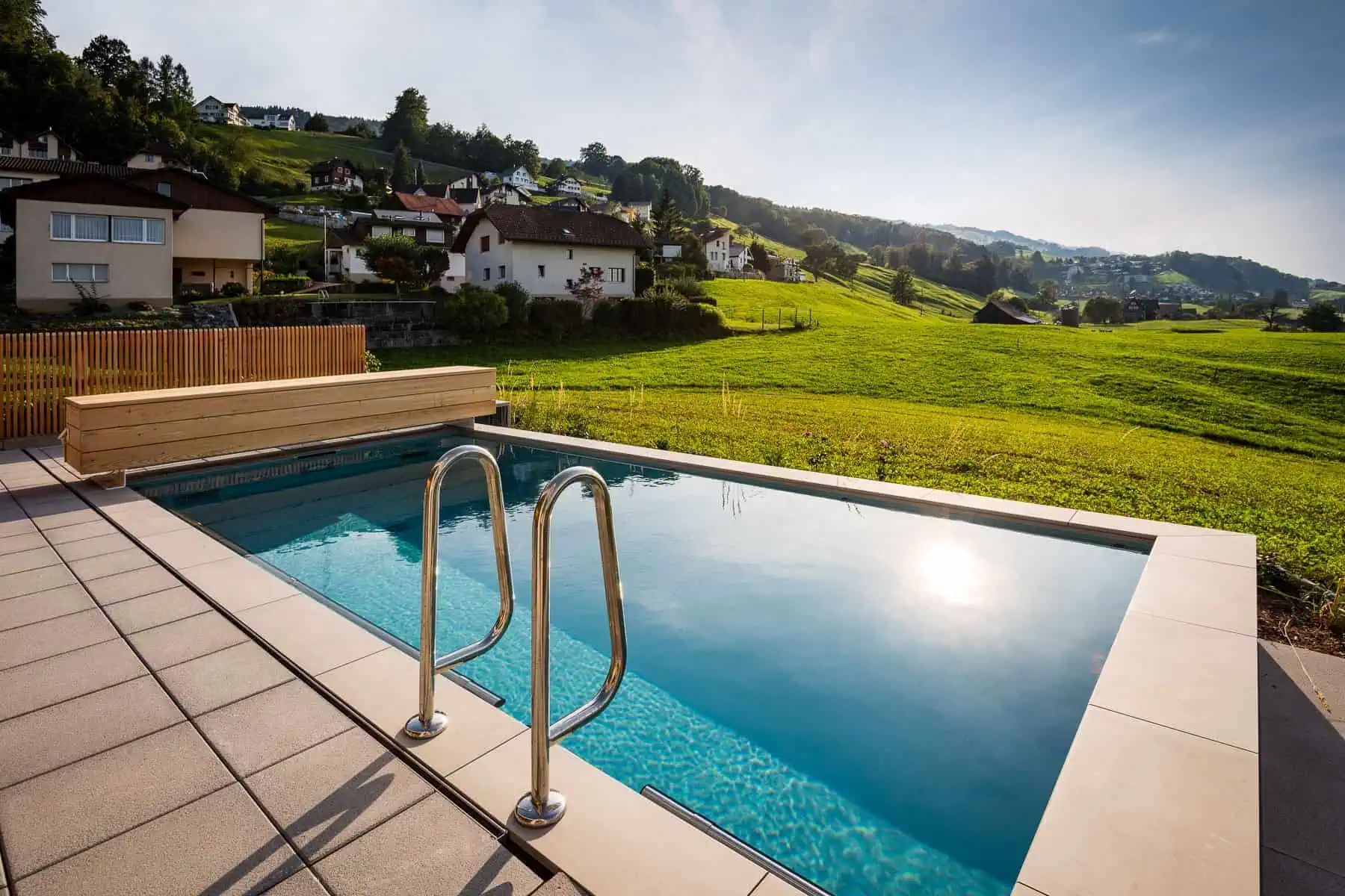 Hochwertiger Pooldeckel vor grünem Landschaftshintergrund, aus langlebigen Materialien, deutsche Ingenieurskunst, sorgt für effiziente Wärmeisolierung und Sicherheit.